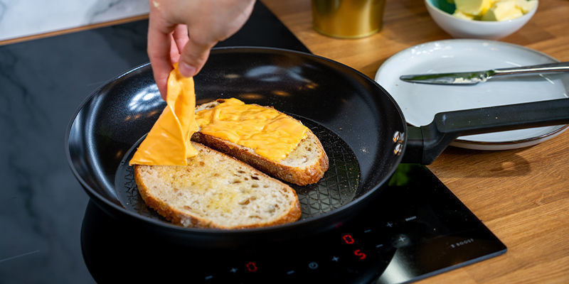 Læg en brødskive på panden med siden med almindeligt smør nedad. Læg osteskiverne ovenpå Læg en brødskive på panden med siden med almindeligt smør nedad. Læg osteskiverne ovenpå