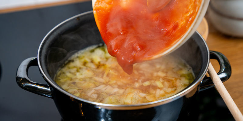 Tilsæt tomaterne eller tomatpuré samt grøntsagsbouillon, og skru ned, så det småsimrer Tilsæt tomaterne eller tomatpuré samt grøntsagsbouillon, og skru ned, så det småsimrer